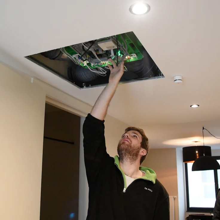 Un technicien DUCO vérifie l'ajustement de la DucoBox montée au plafond