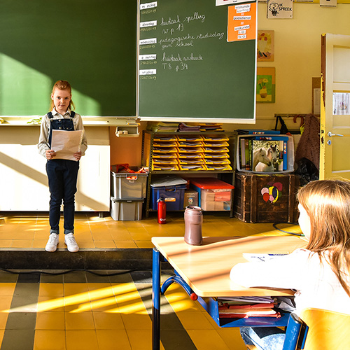 Meisje geeft een presentatie vooraan in de goed geventileerde klas 